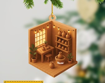 May include: A ceramic studio Christmas ornament in a cube shape, featuring a table, shelves, and a pottery wheel. The ornament is brown with a string of lights and the text "Name can be changed".
