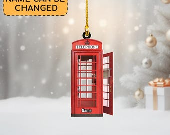 May include: A red telephone booth ornament with an open door, hanging from a gold string. The word "TELEPHONE" is at the top, and "Name" is at the bottom. A yellow sign above says "NAME CAN BE CHANGED".