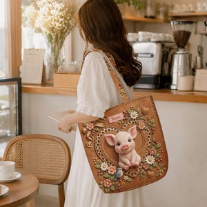 May include: A brown tote bag featuring a central 3D-style piglet illustration inside a heart-shaped frame with leopard print trim. The bag is decorated with sculpted flowers, leaves, a small blue bird, and a rectangular tag labeled Name.