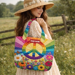 May include: A colorful tote bag with a peace sign design. The bag features a rainbow pattern, a large peace symbol, and a floral design with butterflies. The text "YOUR NAME" is displayed on a red rectangle. The bag has rainbow-striped handles.