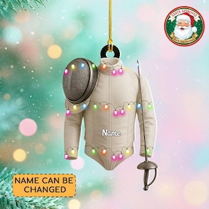 May include: A fencing-themed Christmas ornament featuring a cream-colored fencing jacket, mask, and foil. The ornament is adorned with colorful string lights and has the text "Name" on the jacket. The text "Name can be changed" is also present.