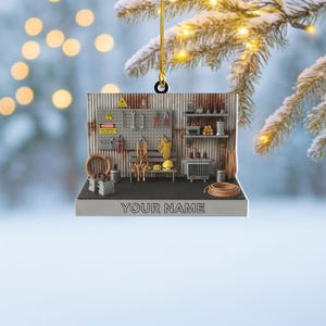 May include: A miniature workshop ornament with tools, equipment, and the text "YOUR NAME". The ornament features a corrugated metal backdrop, a pegboard with tools, and a small bench with a yellow hard hat. A perfect gift for a tradesperson.