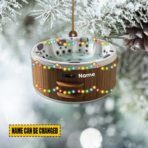 May include: A decorative ornament shaped like a hot tub, with a brown wooden exterior and a white interior. The ornament is adorned with colorful string lights and the word "Name" is displayed on the front. The text "Name Can Be Changed" is also visible.
