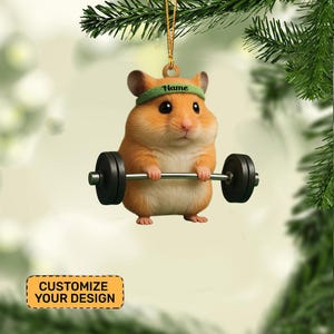 May include: A Christmas ornament featuring a cartoon hamster lifting a barbell. The hamster is orange and white, wearing a green headband with the word "Name" on it. The ornament has a gold string for hanging and the text "CUSTOMIZE YOUR DESIGN".