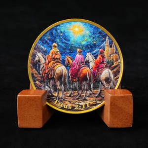 May include: A round, decorative item depicting three figures on horseback, set against a starry night sky with a bright star. The item is supported by a wooden stand. The text "Titus 2:11" is visible.
