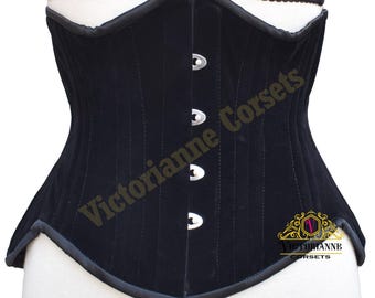 Puede incluir: Un corsé de terciopelo negro con costuras verticales y un ribete de satén. El corsé presenta tres cierres plateados en la parte delantera y está etiquetado como "Victorianne Corsets".