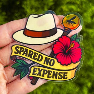 Op de afbeelding: Een sticker met een crèmekleurige fedora met een bruine band, een vergrootglas met een mug, een rode hibiscusbloem en een banner met de tekst "SPARE NO EXPENSE". De sticker heeft een heldere, glanzende afwerking.