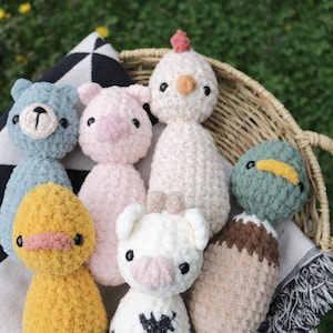 May include: A collection of seven crocheted stuffed animals in a wicker basket. The animals include a bear, pig, chicken, duck, cow, and two other animals. The animals are all different colors and have different features.