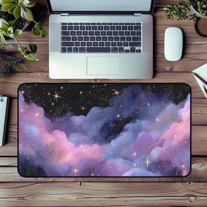 Puede incluir: Alfombrilla de escritorio rectangular con un diseño de acuarela vibrante de un cielo estrellado. Nubes rosas, moradas y azules con estrellas doradas. Se ve un portátil, un ratón y plantas sobre un escritorio de madera.