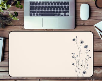 Può includere: Un tappetino da scrivania beige con un bordo nero e un delicato disegno floreale in tonalità di grigio. Il disegno presenta un unico stelo con piccoli fiori e foglie.