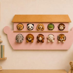 May include: A pink wooden wall-mounted display shaped like a boat with a tan roof. It features ten circular cutouts, each containing a plush animal head: a bear, panda, dog, frog, monkey, elephant, lion, giraffe, sheep, and a tiger.