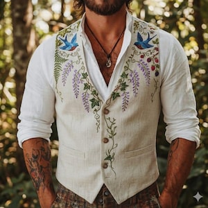 Op de afbeelding: Een beige vest met ingewikkelde borduursels met blauwe vogels, paarse wisteria en groene bladeren. Het vest heeft een knoopsluiting en wordt over een wit overhemd gedragen. De stijl is bohemien en geïnspireerd op de natuur.