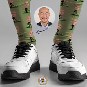 May include: A pair of white sneakers with black laces and soles. The person is wearing green socks with a repeating pattern of a person playing golf and a face. A photo of the person's face is in a blue circle.