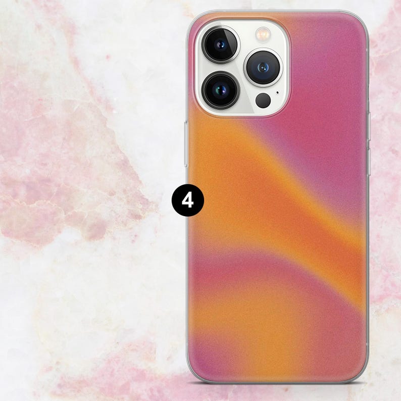 K&ouml;nnte beinhalten: Handyh&uuml;lle mit Farbverlauf in Rosa- und Oranget&ouml;nen. Die H&uuml;lle hat einen transparenten Rand und ist f&uuml;r ein Smartphone mit mehreren Kameralinsen konzipiert.