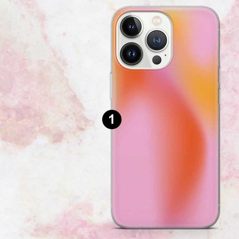 K&ouml;nnte beinhalten: Eine Handyh&uuml;lle mit einem Farbverlauf in Rosa, Orange und Gelb. Die H&uuml;lle hat einen transparenten Rand und einen Kameraausschnitt. Die Gesamt&auml;sthetik ist modern und stilvoll.