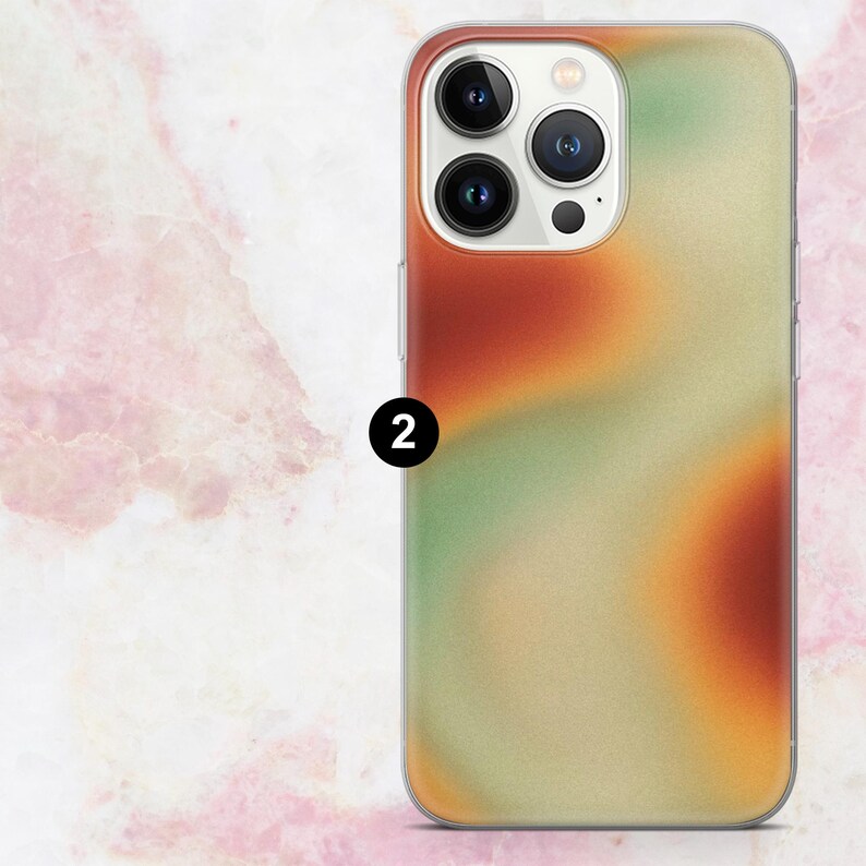 K&ouml;nnte beinhalten: Eine Handyh&uuml;lle mit einem farbenfrohen, abstrakten Design. Die H&uuml;lle weist eine Mischung aus Orange-, Gr&uuml;n- und Beiget&ouml;nen auf. Die Handyh&uuml;lle hat einen transparenten Rand und einen Kameraausschnitt. Die Zahl "2" ist auf der H&uuml;lle aufgedruckt.