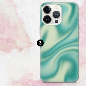 K&ouml;nnte beinhalten: Eine Smartphone-H&uuml;lle mit einem wirbelnden, abstrakten Design in T&uuml;rkis- und hellgr&uuml;nen Farbt&ouml;nen. Die H&uuml;lle hat einen transparenten Rand und ein gl&auml;nzendes Finish. Die Kameralinsen des Telefons sind oben sichtbar.
