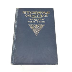 Può includere: Un libro vintage blu scuro intitolato "Fifty Contemporary One-Act Plays" di Frank Shay e Pierre Loving. La copertina presenta scritte dorate e un emblema decorativo.