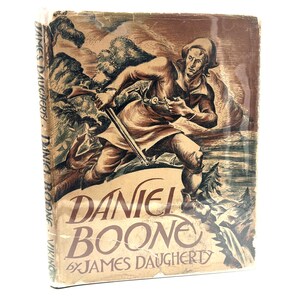 May include: A hardcover book titled Daniel Boone by James Daugherty with a brown and tan illustrated dust jacket. The cover features a drawing of a person in a hat holding a long rifle in a wooded landscape. The spine displays the author and title.