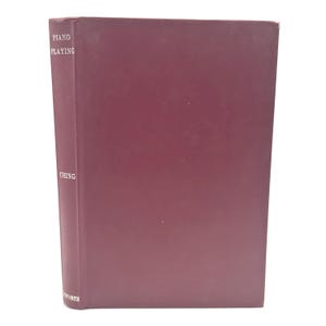 May include: A maroon-colored book titled "Piano Playing" with the author's name, "Ching," visible on the spine. The book has a solid maroon cover and is set against a white background.