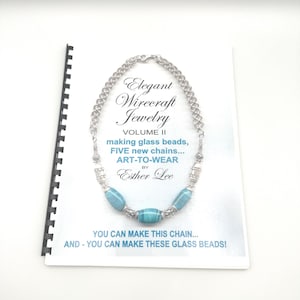Puede incluir: Un libro de instrucciones con encuadernación en espiral titulado Elegant Wirecraft Jewelry Volume II de Esther Lee, que muestra un collar de cadena plateada con cuentas de vidrio veteadas en azul claro y blanco con el texto YOU CAN MAKE THIS CHAIN.