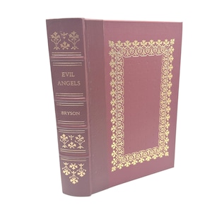 Könnte beinhalten: Ein weinrotes Buch mit dem Titel "EVIL ANGELS" von Bryson. Das Buch hat goldene Zierakzente auf dem Buchrücken und einen goldenen, verzierten Rahmen auf dem vorderen Einband. Das Buch ist vor einem weißen Hintergrund platziert.