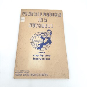 May include: A tan instructional booklet titled Ventriloquism in a Nutshell with blue text and a graphic of a ventriloquist dummy sitting inside a walnut shell. The cover includes the text Ten Complete Lessons From Maher Ventriloquist Studios.