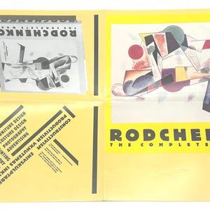 Op de afbeelding: Een gele poster met zwarte tekst die "Rodchenko The Complete Work" luidt. De poster toont een geometrisch abstract schilderij in rood, geel, blauw, zwart en wit.