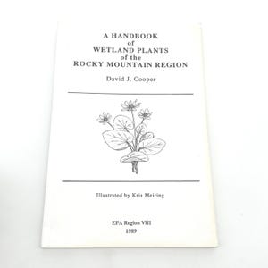 May include: A Handbook of Wetland Plants of the Rocky Mountain Region by David J. Cooper. The cover features a botanical illustration of a plant with flowers. Illustrated by Kris Meiring. Published by EPA Region VIII in 1989.