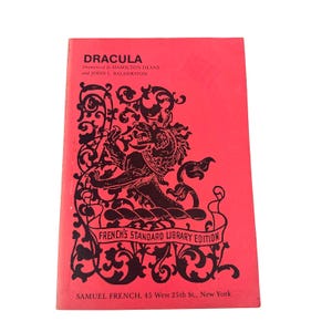 May include: A bright red paperback book titled Dracula, dramatized by Hamilton Deane and John L. Balderston. The cover features a black graphic of a heraldic creature surrounded by ornate scrollwork and the text French's Standard Library Edition.