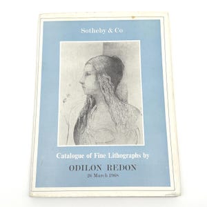 May include: A vintage Sotheby & Co. catalog featuring a portrait of a woman. The cover is light blue with the text "Catalogue of Fine Lithographs by ODILON REDON 26 March 1968". The catalog is in good condition.