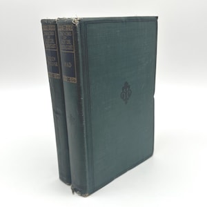 以下が含まれることがあります： 濃い緑色の表紙の2冊のアンティーク本。「The Works of Guy De Maupassant」のタイトルが金色の文字で書かれています。右の本の表紙には装飾的なエンブレムがあります。