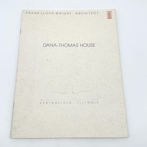 Puede incluir: Folleto beige con el texto "FRANK LLOYD WRIGHT ARCHITECT" en la parte superior. El título "DANA-THOMAS HOUSE" está centrado, con un dibujo de una casa debajo. El texto "SPRINGFIELD ILLINOIS" está en la parte inferior.