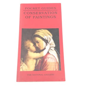 Könnte beinhalten: Ein rotes Taschenbuch mit dem Titel "Pocket Guides Conservation of Paintings" mit einem Bild von Mutter und Kind. Das Buch stammt von der National Gallery. Das Cover zeigt ein Gemälde mit sanften Farben.