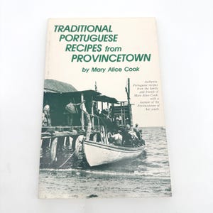 Könnte beinhalten: Ein Vintage-Kochbuch mit dem Titel "Traditional Portuguese Recipes from Provincetown" von Mary Alice Cook. Das Cover zeigt ein Schwarz-Weiß-Bild eines Bootes und eines Piers mit grünem Text. Das Buch enthält authentische portugiesische Rezepte und eine Memoiren.