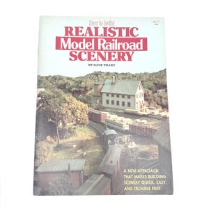 May include: A book titled "How to Build Realistic Model Railroad Scenery" by Dave Frary. The cover features a detailed model railroad scene with buildings, trees, and trains. The text on the cover also states "A new approach that makes building scenery quick, easy, and trouble free."