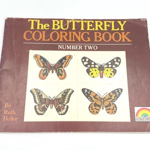 May include: A brown softcover book titled The BUTTERFLY COLORING BOOK NUMBER TWO by Ruth Heller. The cover features four distinct butterfly illustrations in a grid, with a small rainbow logo in the bottom right corner and the number 10149.