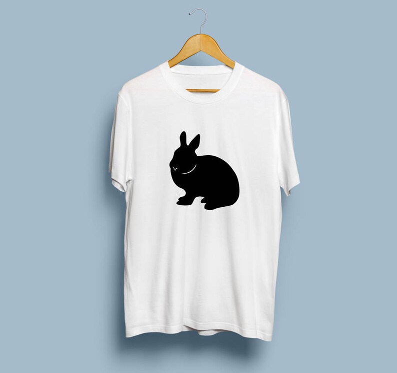 May include: White t-shirt with a black silhouette of a rabbit.