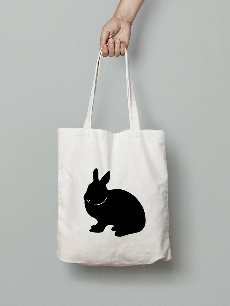 May include: A white canvas tote bag with a black silhouette of a rabbit printed on the front.