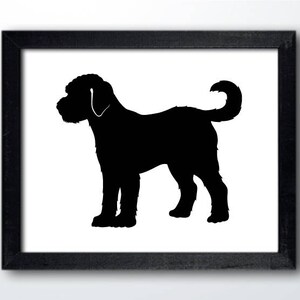 May include: Black silhouette of a dog with a curly tail, standing on a white background. The dog is facing to the left, with its head turned slightly to the right. The silhouette is framed by a black frame.