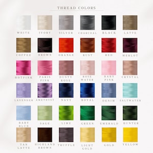 Op de afbeelding: Een kleurenkaart met een verscheidenheid aan draadkleuren. De kaart bevat tinten als wit, ivoor, zilver, houtskool, zwart en latte. Andere kleuren zijn oranje, rood, roze, blauw, groen en goud. De tekst "THREAD COLORS" staat bovenaan.