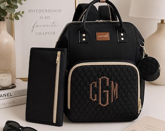 Può includere: Uno zaino nero con cerniere e dettagli dorati, caratterizzato da una tasca frontale trapuntata con un monogramma ricamato delle lettere CGM. Il set include una pochette rettangolare abbinata e un piccolo astuccio circolare con cerniera.