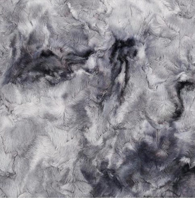 May include: A close-up of a plush fabric with a marbled appearance. The fabric features a blend of gray and charcoal hues, creating a soft, textured surface. The design resembles a flowing, abstract pattern.
