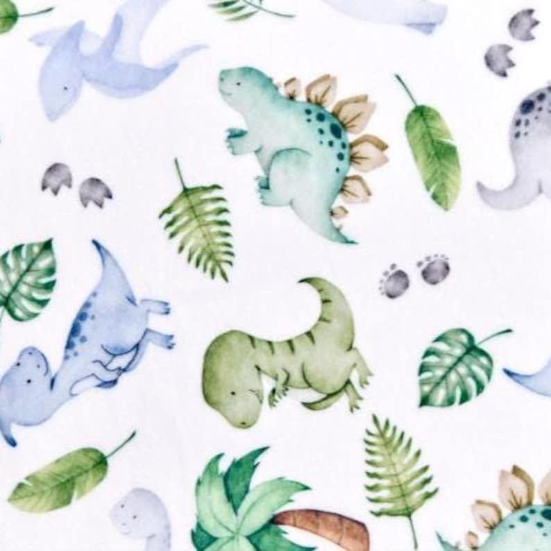 Op de afbeelding: Waterverfpatroon met verschillende dinosaurussen in blauw, groen en grijs, samen met groene bladeren en palmbomen op een witte achtergrond. Het ontwerp bevat verschillende dinosaurussoorten en voetafdrukken.