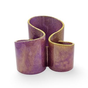 May include: A purple and gold glitter resin desk organiser with three compartments. The organiser is shaped like a figure of eight.