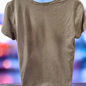 May include: A short-sleeved, crew neck t-shirt in a muted, earthy brown colour. The shirt has a simple, classic design, with a rounded neckline and short sleeves. The fabric appears to be soft and lightweight.