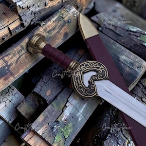 May include: A short sword with a metallic silver blade, a dark red grip, and an ornate bronze-coloured crossguard featuring intricate scrollwork. The sword includes a matching dark red scabbard with a bronze-coloured tip, resting together.