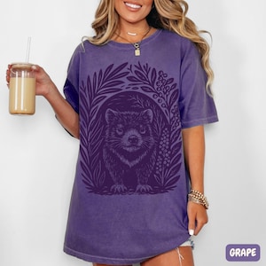 Hand-carved linocut Tasmanian Devil illustration with stylized foliage, minimalist wildlife art printed on cotton t-shirt on purple color