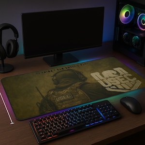 Puede incluir: Alfombrilla de ratón para juegos rectangular con diseño militar. La alfombrilla presenta un gráfico de soldado, el texto "USEC" y la cita "I THINK I CAN STILL I PAT". También se ven un teclado, un ratón y un monitor.