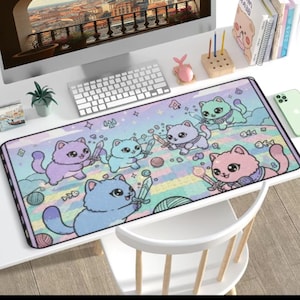 May include: A rectangular desk mat featuring a pastel rainbow background with cartoon cats holding swords. The cats are in shades of blue, purple, and pink. The mat includes yarn balls and fish icons.